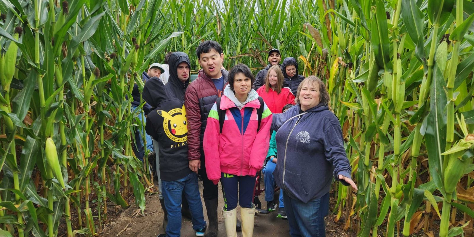 A group of Tavon members posing in between two walls of corn in a corn maze